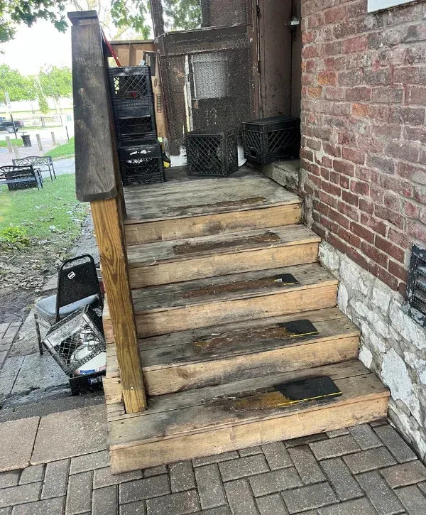 A close-up shot showing the junction between weathered wooden planks and an old, red brick wall with crumbling mortar.