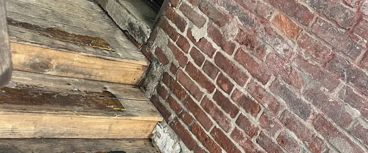 Weathered wooden steps leading to a brick building, with several black milk crates stacked on and beside them.