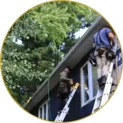 Two professional roofers on ladders repairing a residential roof with safety gear and tools