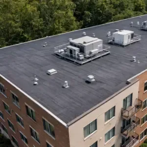 Apartment building with modified bitumen roofing, rooftop units, vents, and clean flat roof surface