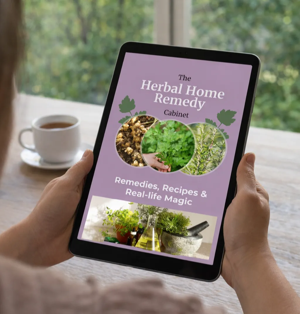 Mockup of the Herbal Home Remedy Cabinet ebook on a cozy kitchen table with herbs