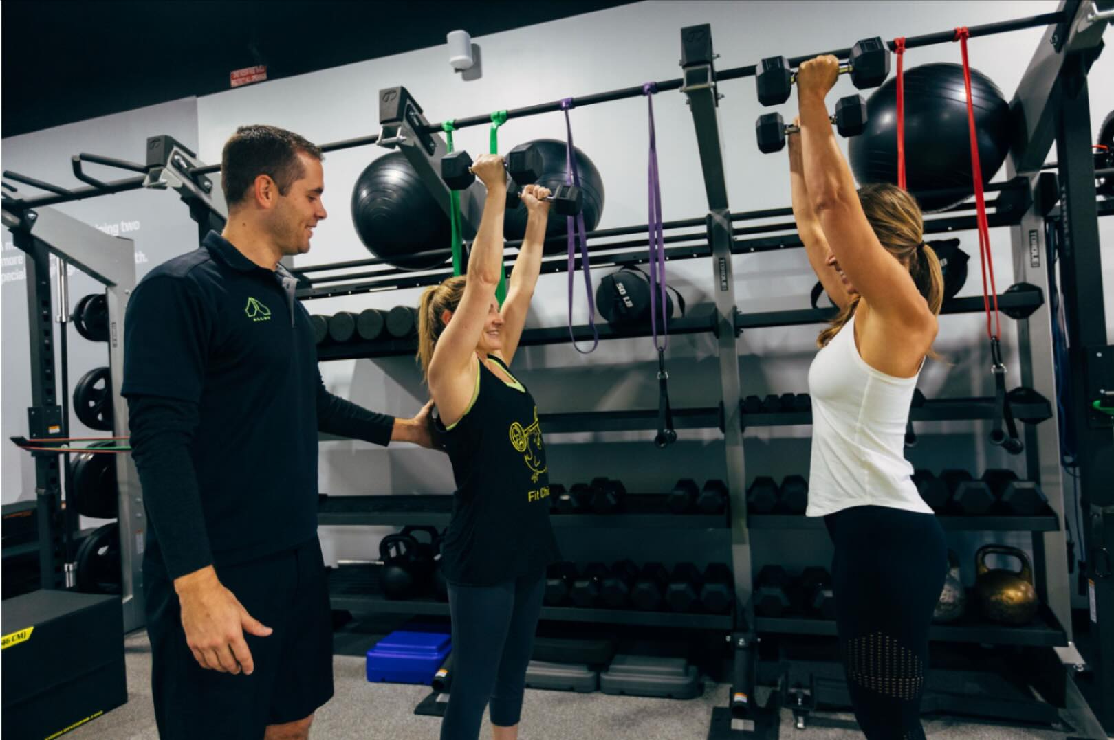 Personal trainer coaching women doing dumbbell strength training exercises in small group fitness classes in Royal Oak MI fitness studio