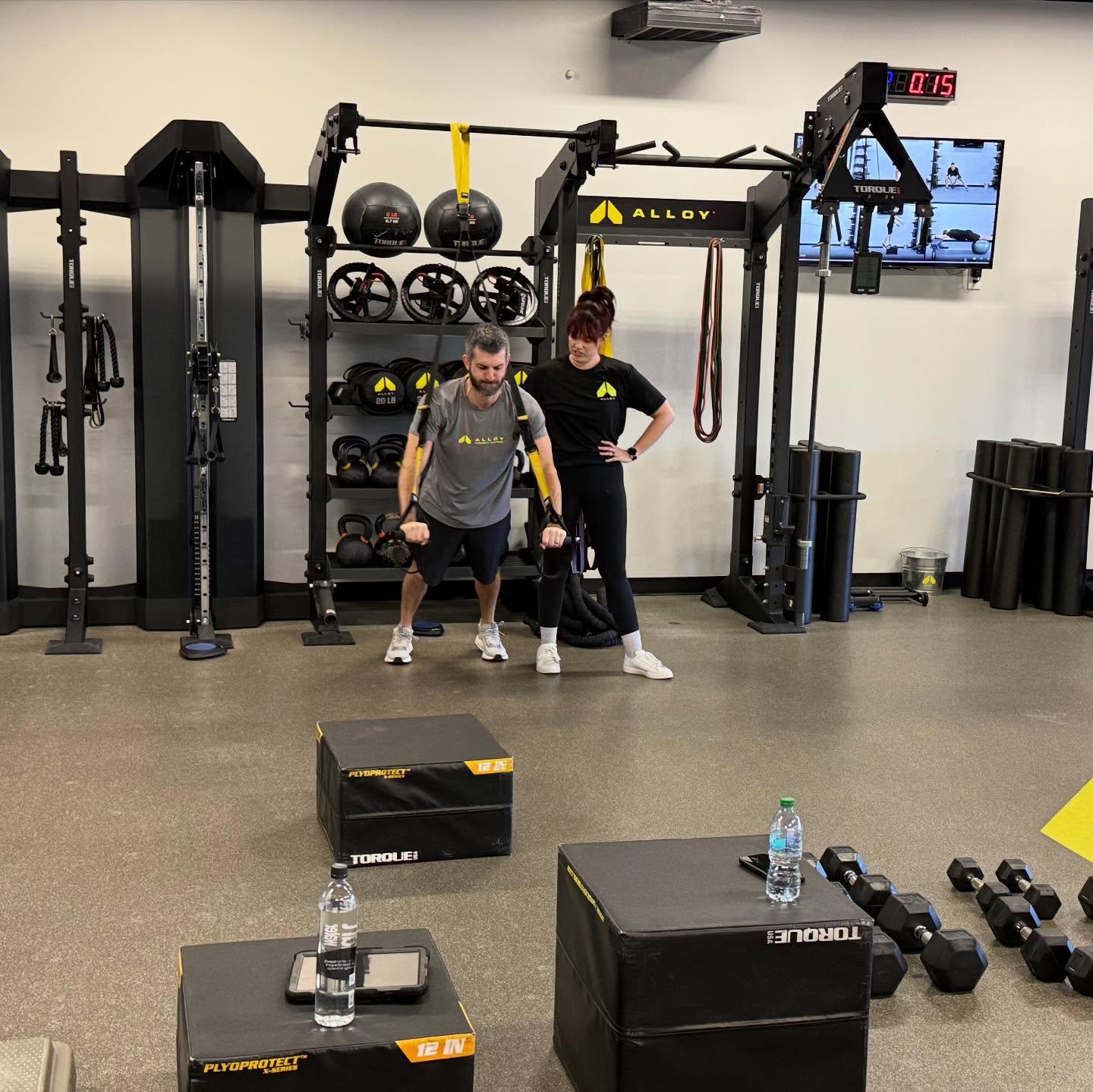 Personal trainer coaching client doing TRX strength training exercise in small group personal training studio in Royal Oak MI focused on functional fitness