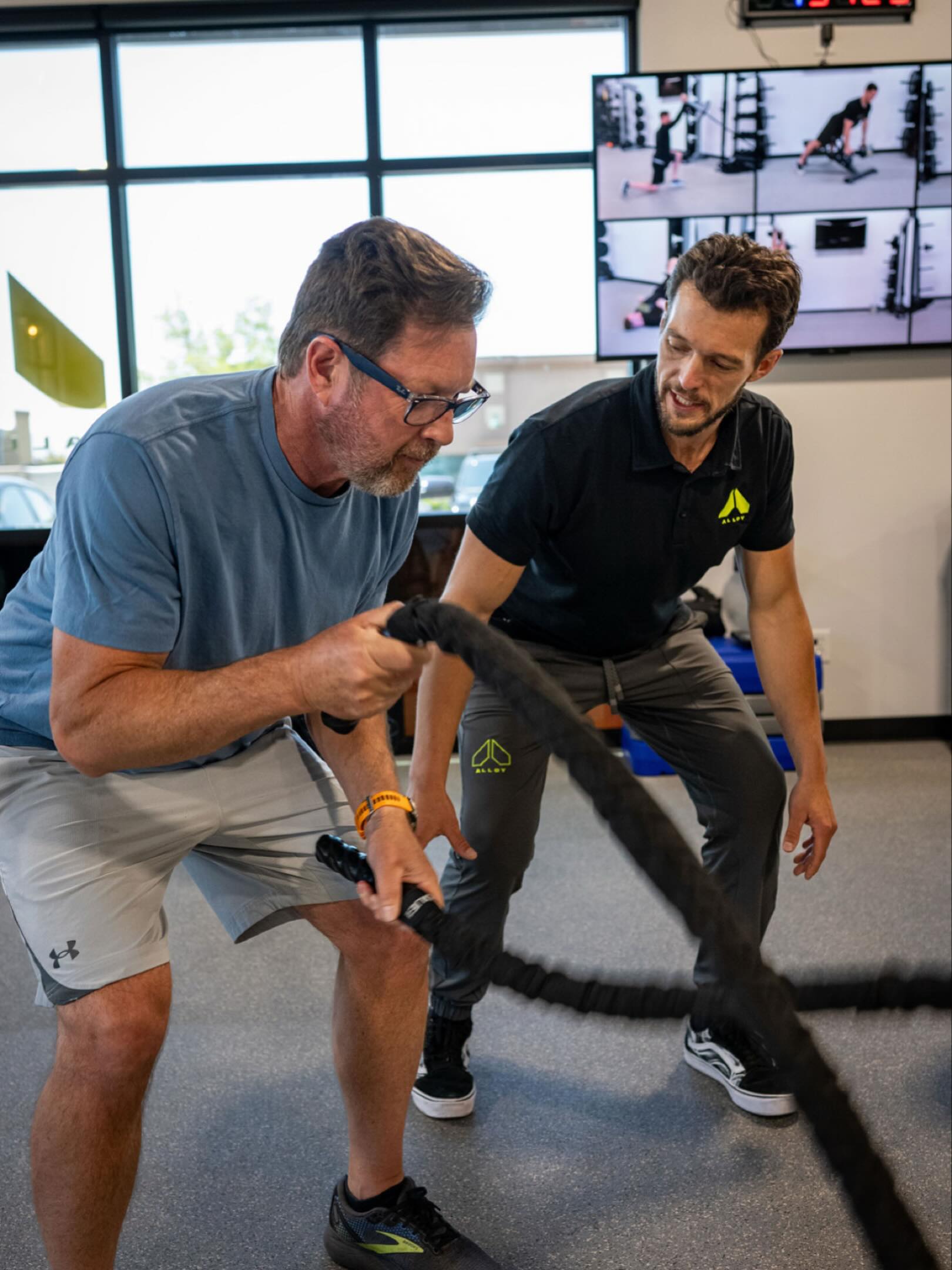 Personal trainer coaching client doing battle rope strength training exercise in fitness studio in Royal Oak MI focused on functional strength and resistance training