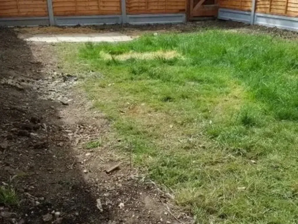 Patchy lawn with bare soil before artificial grass installation