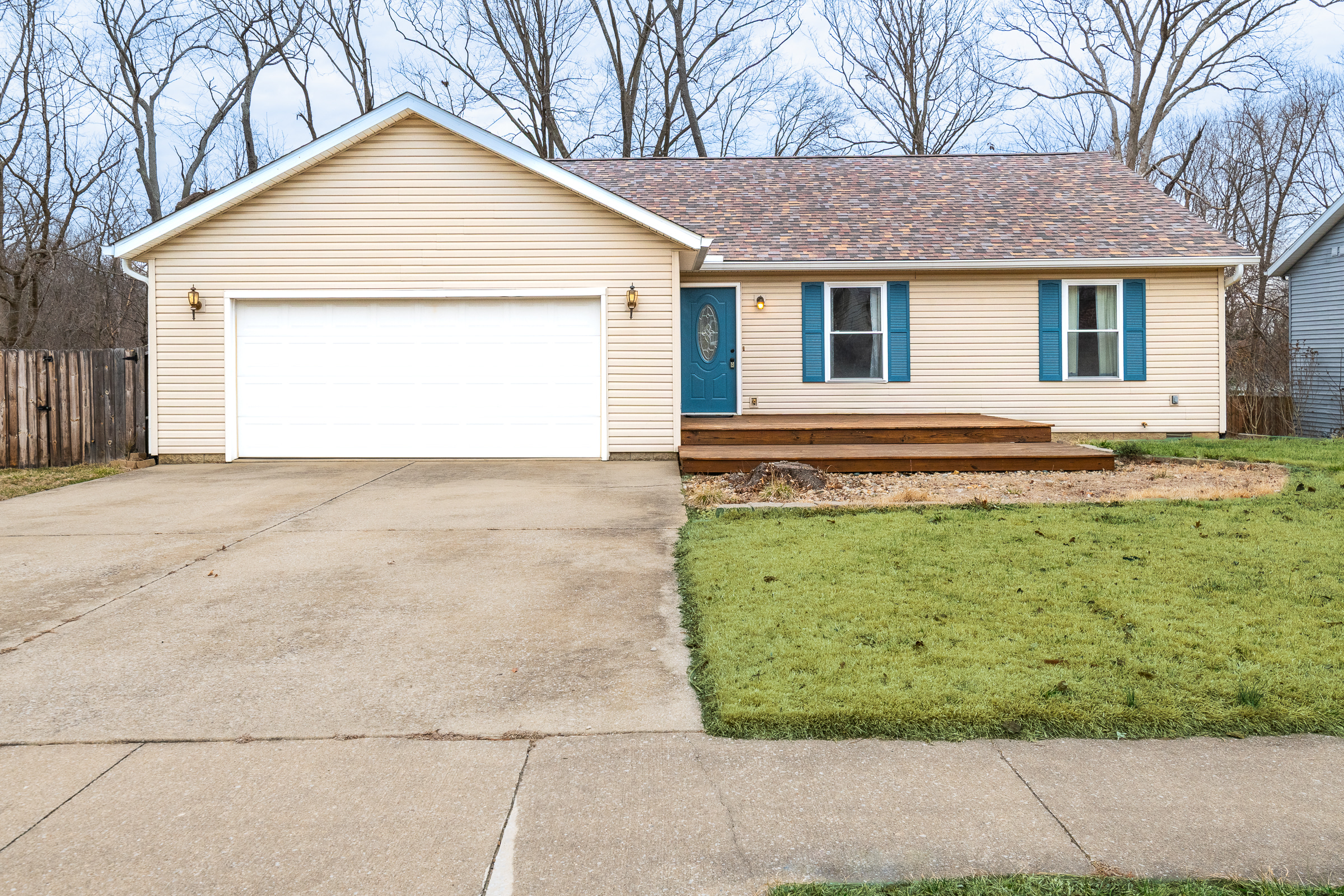 Bloomington Indiana ranch home with blue front door, attached garage, driveway, and front lawn
