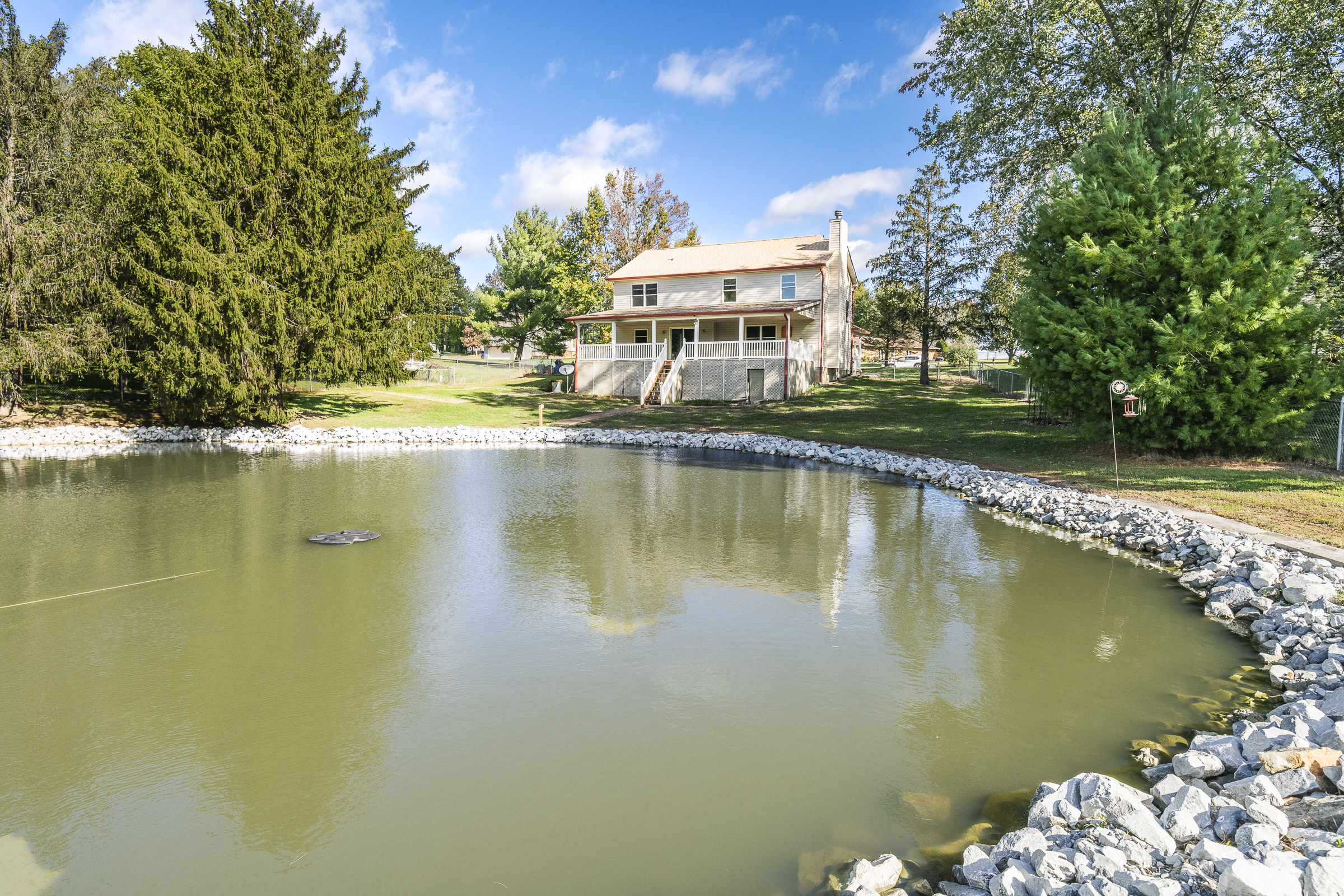 Bloomington Indiana home with pond view, mature trees, backyard green space, and peaceful outdoor setting