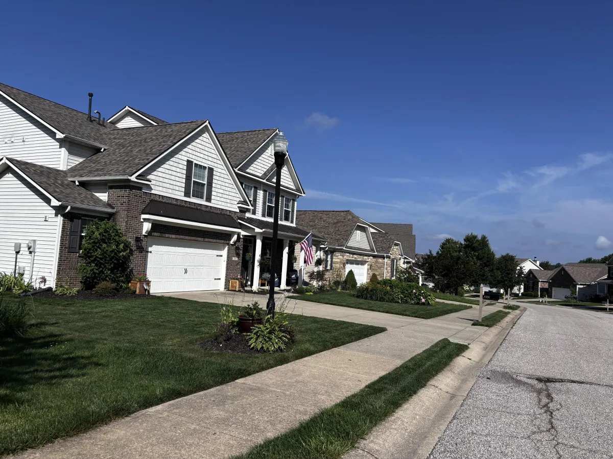 Two-story brick and vinyl-sided home with covered front porch and two-car garage on a landscaped street in the Stonechase neighborhood on Bloomington's west side. (162 characters)