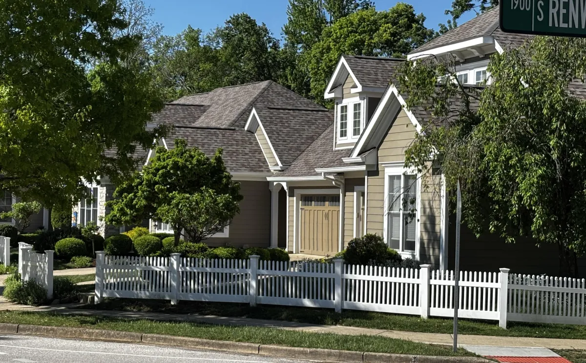 Craftsman-style tan condo with white picket fence and mature shade trees on S Renwick in Bloomington Indiana