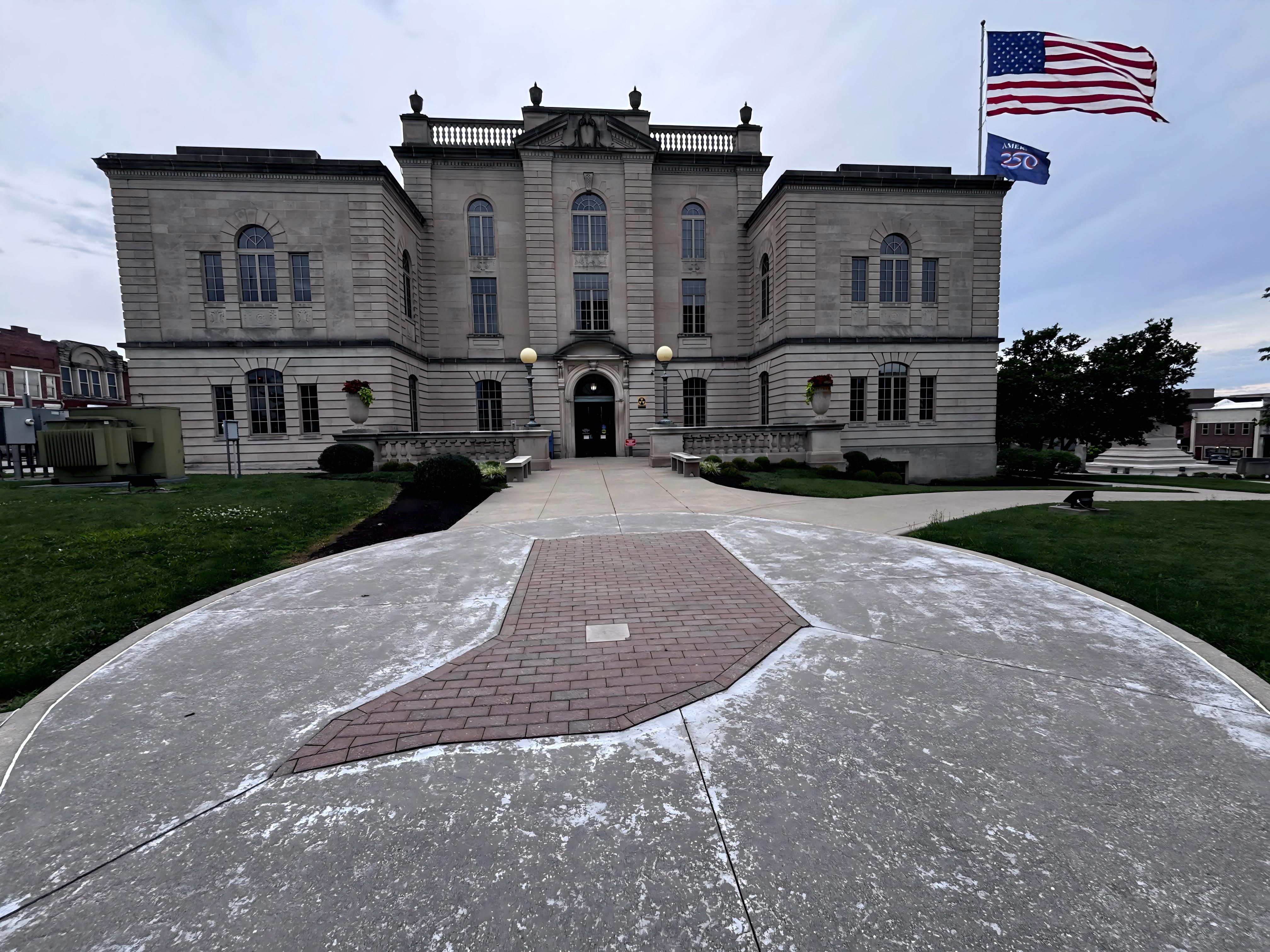 Historic limestone courthouse in south-central Indiana, with columned facade, arched windows, an American flag, and a brick walkway leading to the entrance