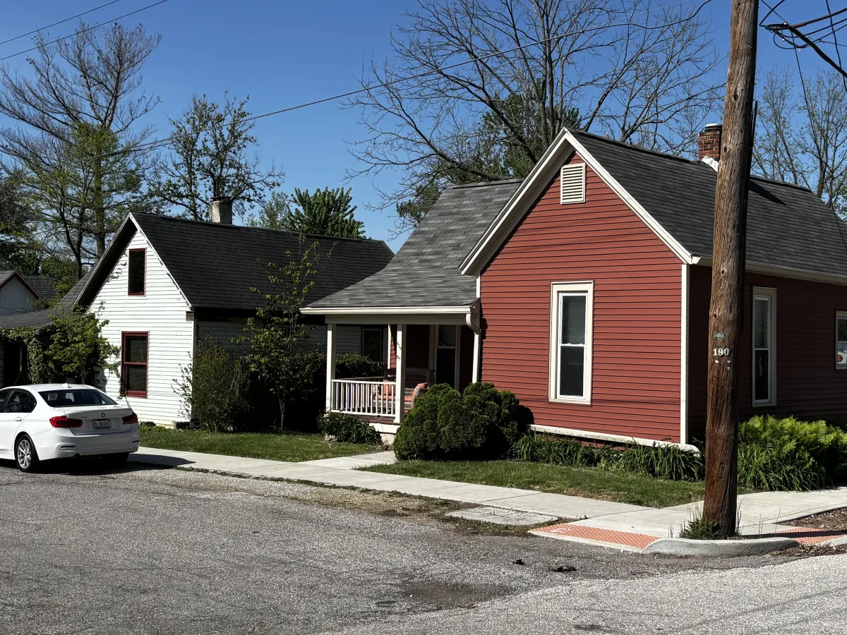 A historic red cottage with a front porch and gabled roof, featuring architecture typical of homes found in Bloomington's Prospect Hill neighborhood.