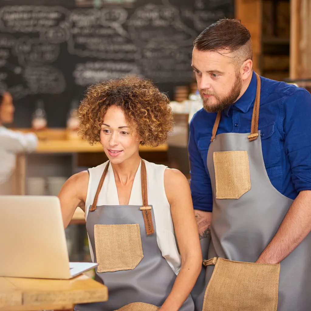 Small business owners reviewing automation strategy on a laptop inside their café