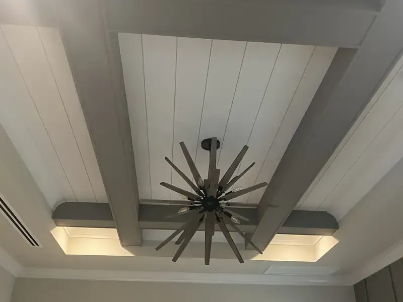 Sophisticated custom coffered ceiling with white shiplap inserts and thick grey wooden beams, featuring a modern sunburst chandelier, installed by Brothers Home Group in Naples, FL.
