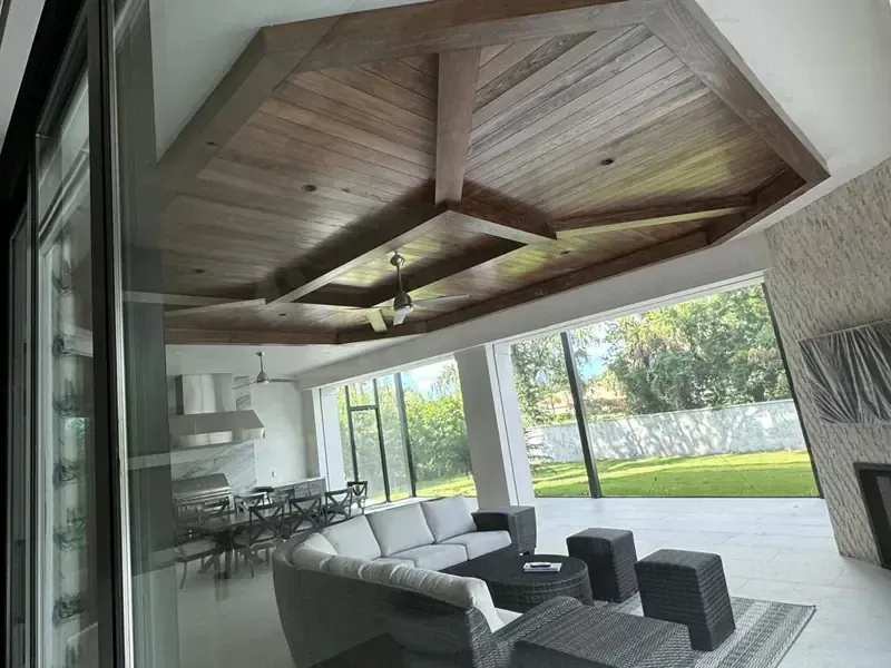Massive custom geometric dark wood ceiling for an outdoor patio (lanai), showcasing high-end exterior finish carpentry by Brothers Home Group.