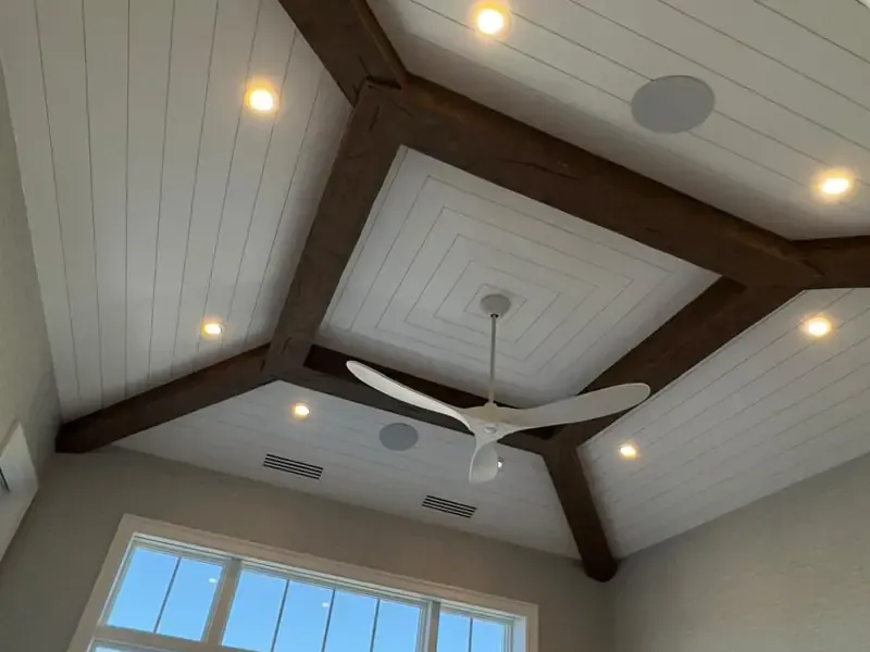High vaulted white ceiling with bold black accent beams and modern pendant lighting, precision-installed for a contemporary Naples residence.