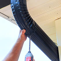 Technician installing a new flexible downpipe system beneath a roof gutter.
