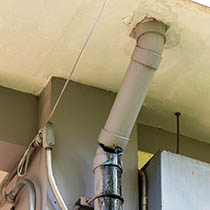 Cracked and poorly sealed downpipe connection causing potential water leaks.