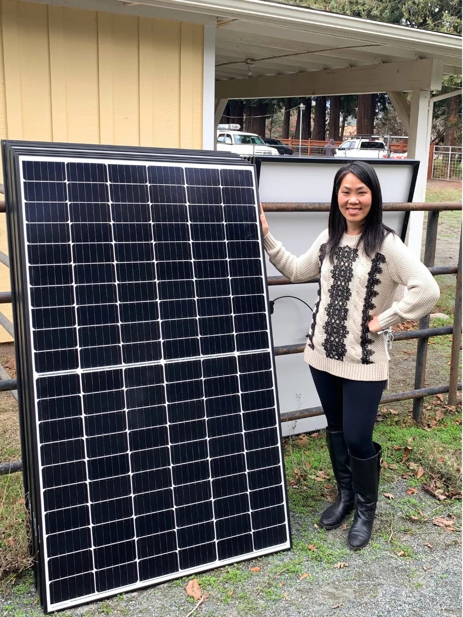Jaime Greene the Solar Queen standing with solar panels