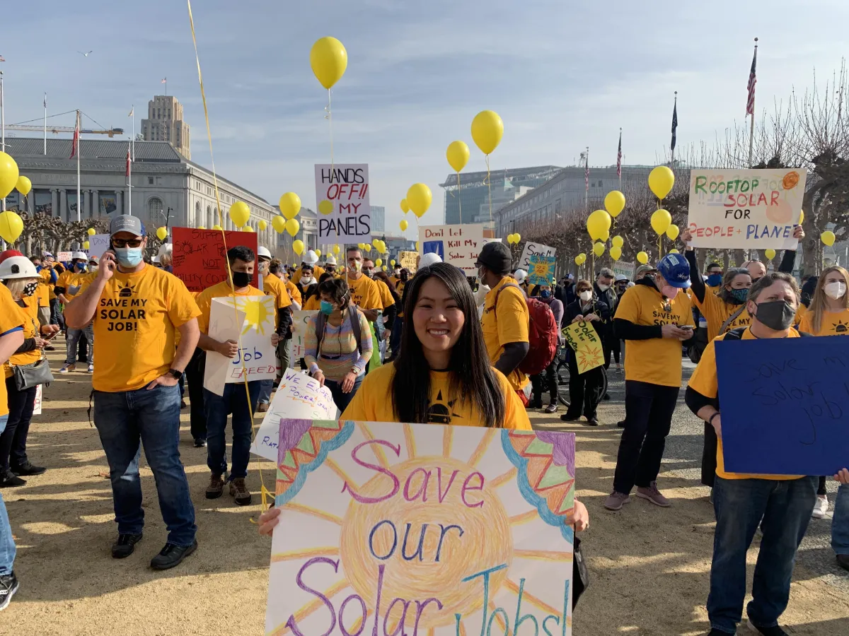 Jaime Greene the Solar Queen holding a sign at a rally