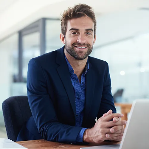 Business professional with improved posture smiling while working pain-free at a computer