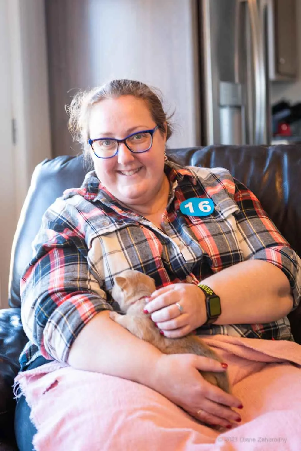 Woman in plaid shirt holding blonde puppy