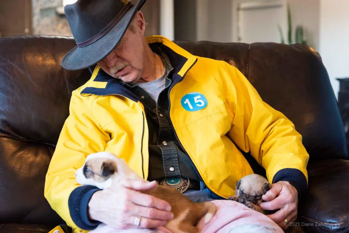 Man in yellow coat holding puppy