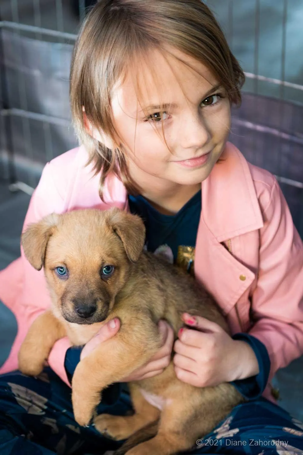 Girl in pink jacket holding puppy
