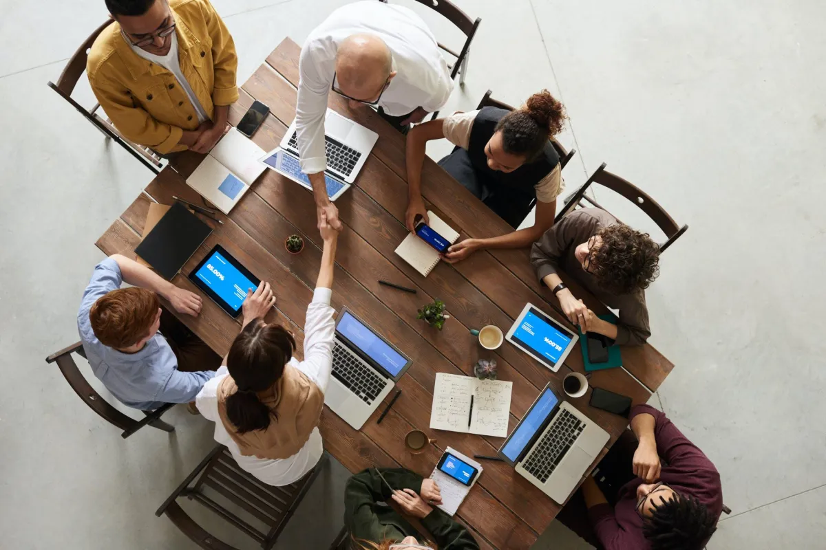 A collaborative scene captured from above: a group of people gathered around a table, laptops open, working together seamlessly.