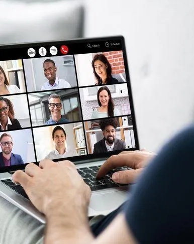 Image of laptop on someone's lap showing a online meeting with 9 images.