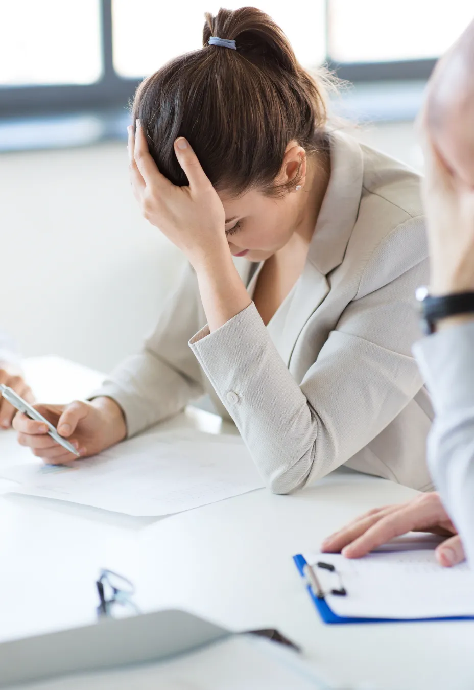 Frustrated female professional at her desk, highlighting the urgency of talent retention strategies during high-stakes M&A integrations.