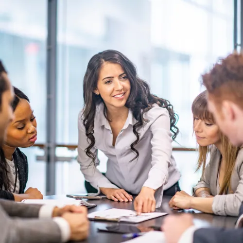 Business professionals smiling while collaborating on a computer, representing success in M&A talent retention strategies.