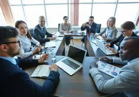 M&A professionals engaged in interactive Boston Summit session with laptops and workbooks, participating in hands-on learning designed for immediate application to merger challenges