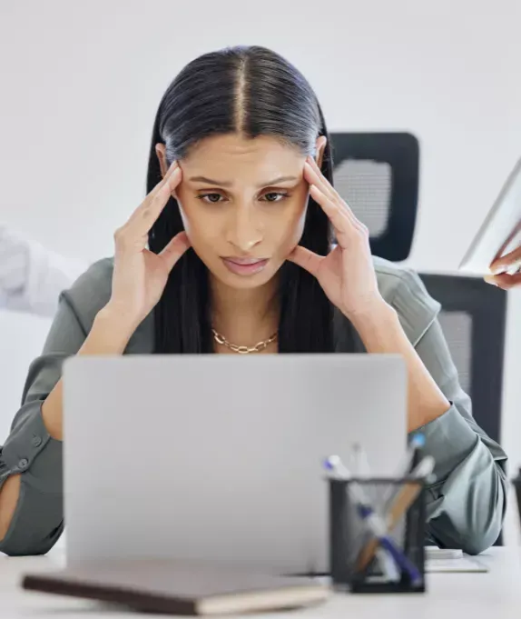 Leader overwhelmed by M&A deal complexity and people challenges while reviewing work on a laptop