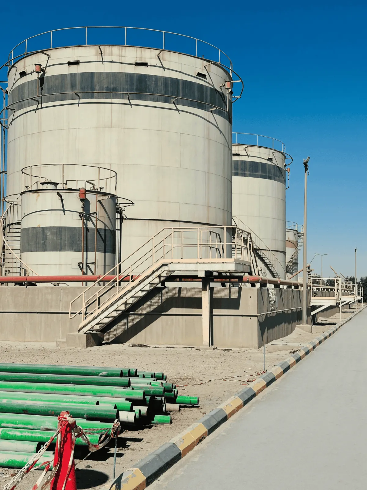 Industrial storage tanks with metal staircases under clear blue sky, green pipes in foreground, showing Custom Industrial Fabrication Projects In West Mountain, Utah.