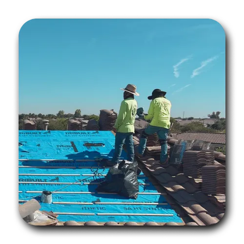 Roofing contractors in San Tan Valley installing blue TRI-BUILT synthetic underlayment on a residential tile roof.