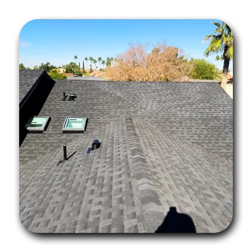 Wide view of a dark architectural shingle roof with skylights, recently serviced by best roofing contractors queen creek Arizona.