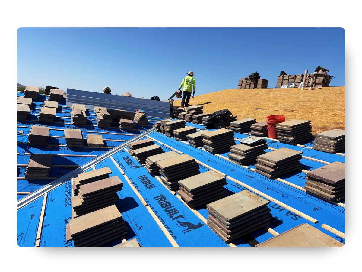 Roofing professional performing residential roof repair in Gilbert on a roof with blue underlayment and stacked tiles.