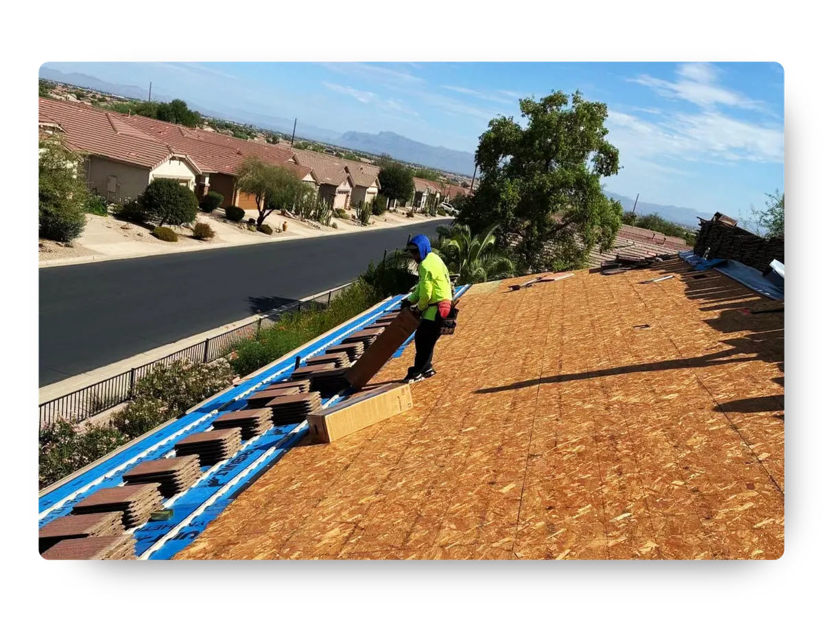 Roofer laying blue synthetic underlayment and stacking tiles on a fresh wood deck during a roof replacement Florence AZ.
