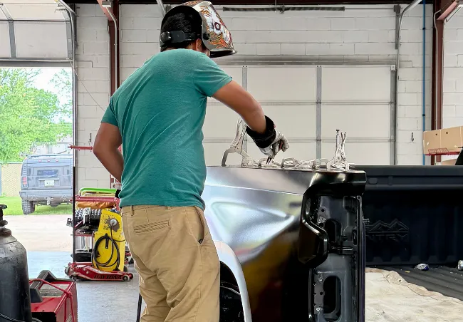 a body shop tech prepping a truck bed skin to be welded