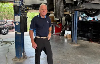 Bobby Fuentes standing next to a van on a lift at B&D Collision in Mesquite