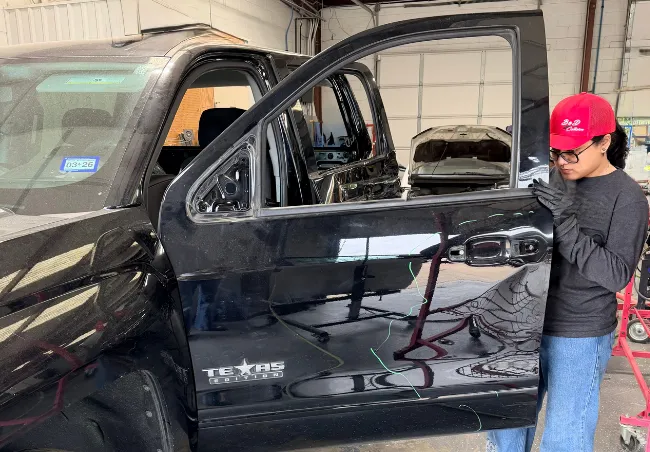 Female collision tech working on a black 4-door truck at B&D in Mesquite