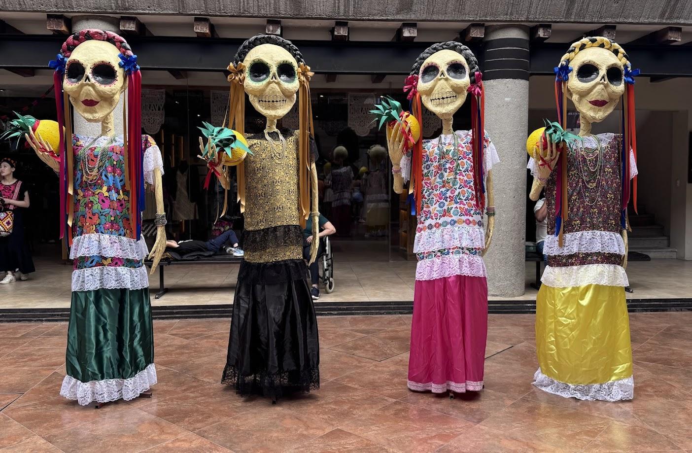 four day of the dead catrinas dressed in typical oaxacan dress that are colorful 