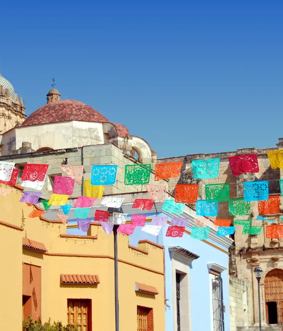 Oaxacan Street, blue sky, church in background and papel picado 