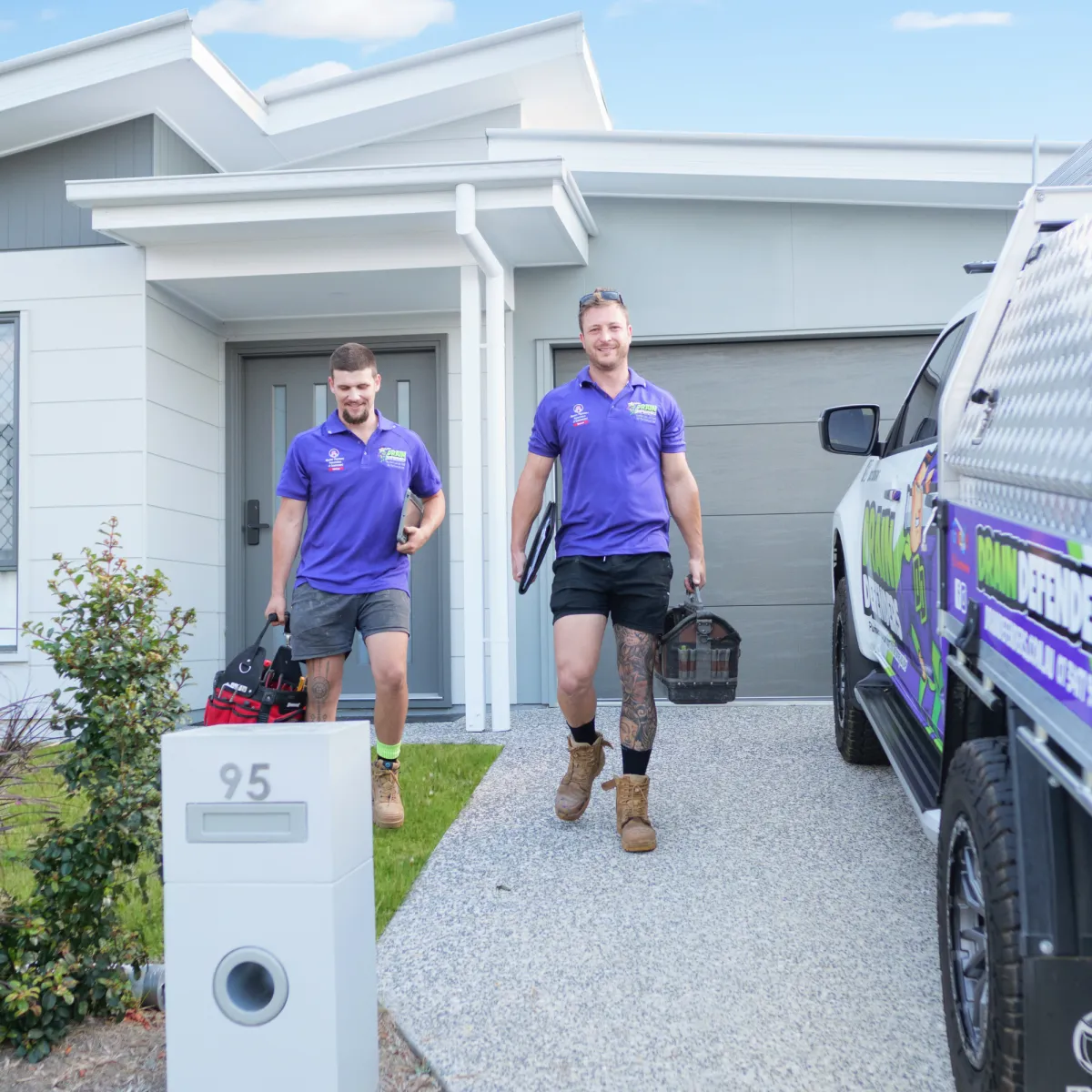 A person stands near a trash can outdoors.
