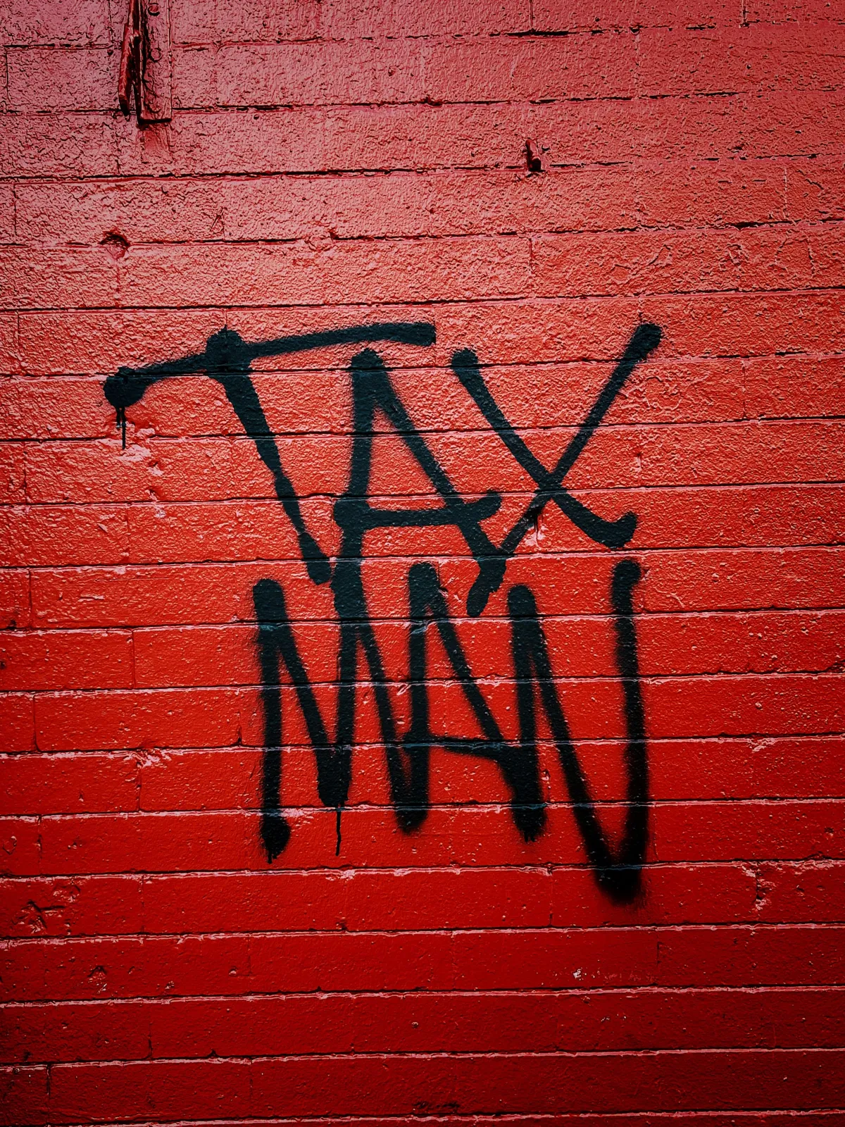 A red wall with 'Tax Man' in grafitti