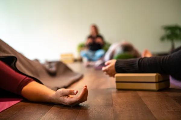 Yoga student relaxing on the floor in a calm class with a yoga block nearby.