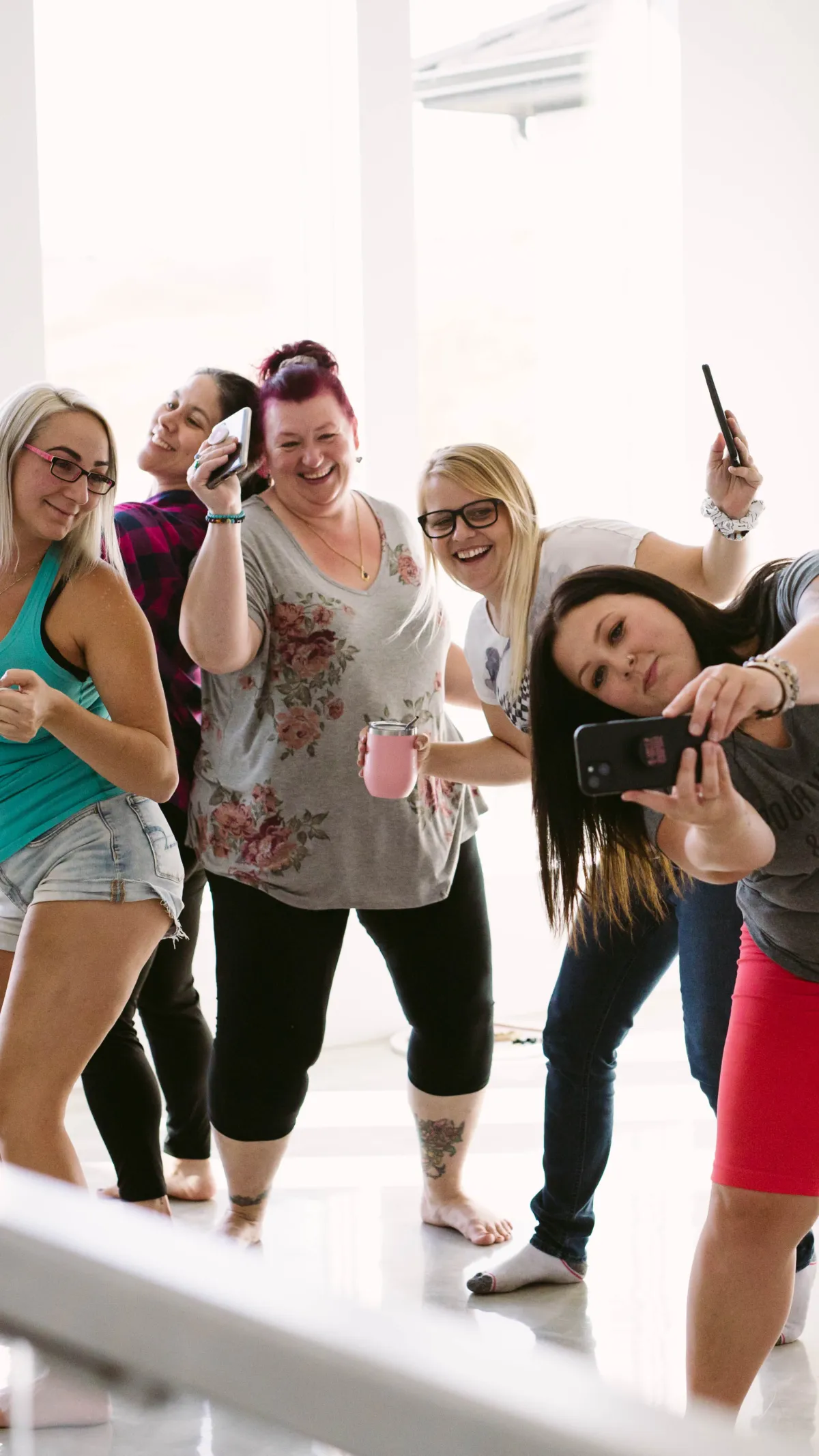 A group of women in many different sizes and hair colours stand together laughing. 