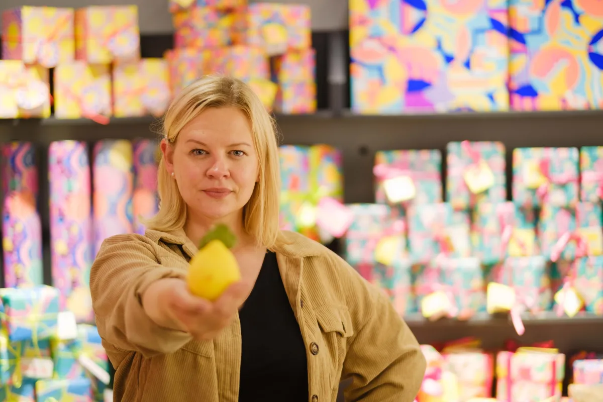 Photograph of founder Cheryl Devlin holding out a lemon in Lush. Photographed in Lush, Glasgow by Victoria Rose Photography