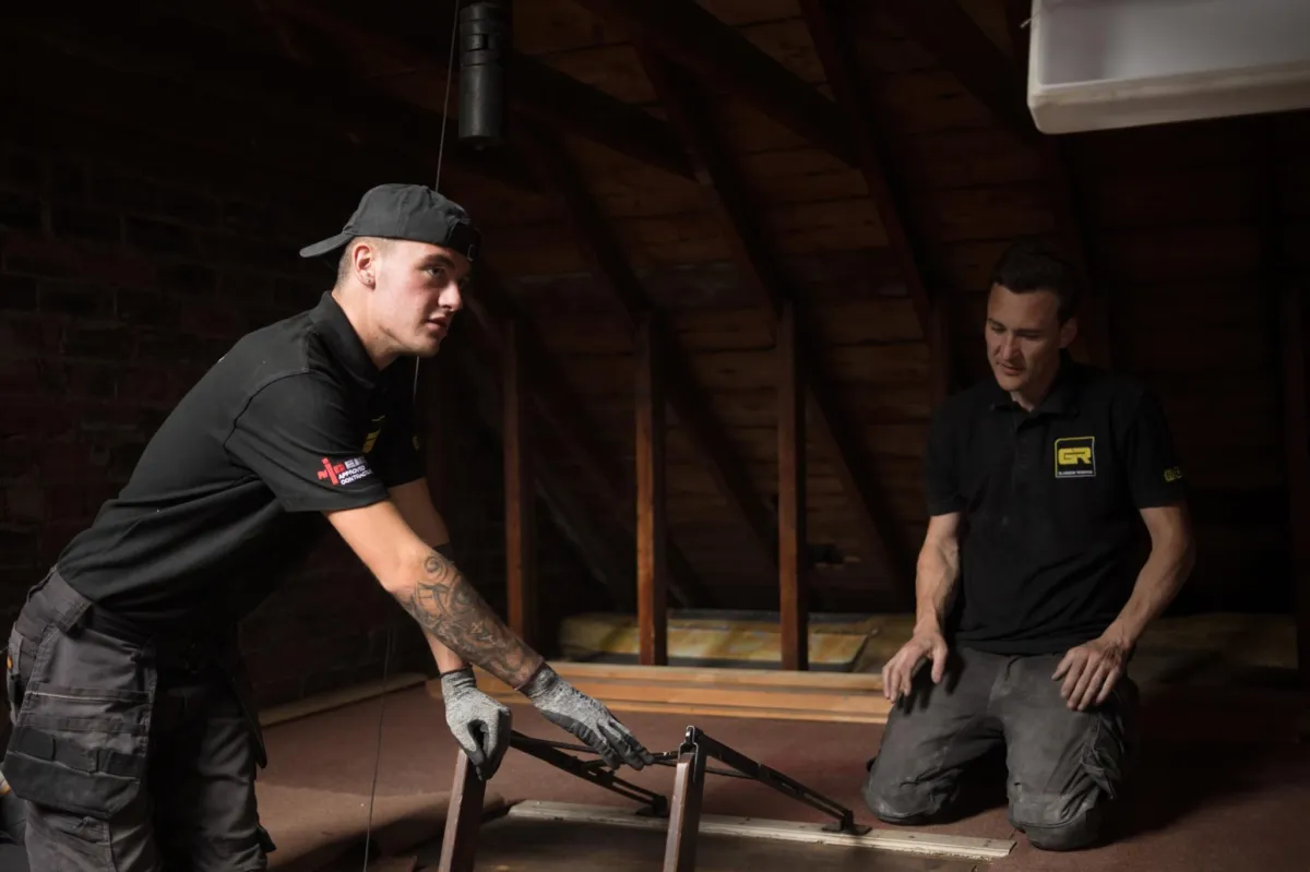 Two electricians installing wiring in loft, Glasgow rewires project — professional site photography.