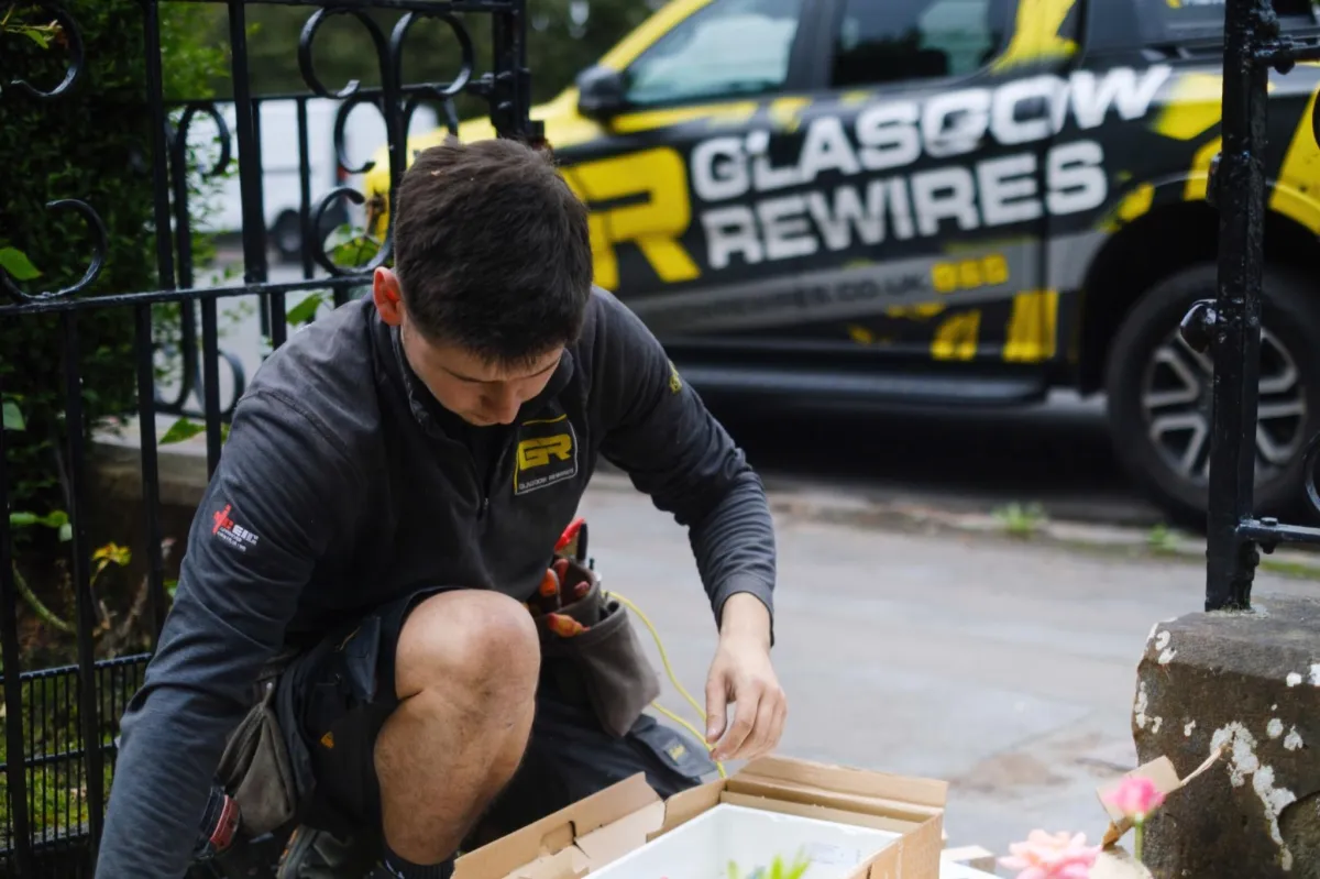 Electrician working outside Glasgow property with branded van — trades photography Scotland.